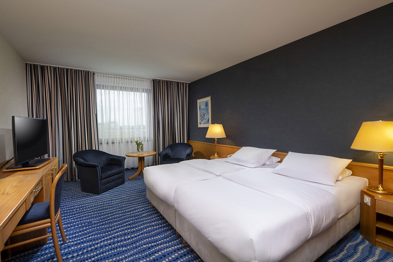 Comfort double room with seating area, desk, and modern artwork on the wall