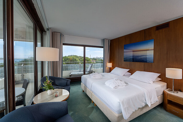 SuperiorPlus Room facing the sea with double bed, seating area and views of the Baltic Sea and greenery
