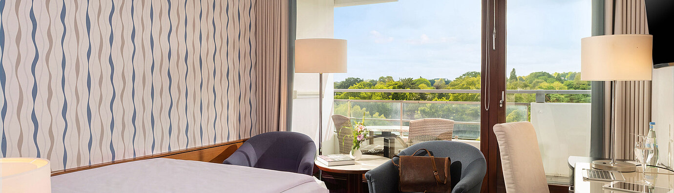 Classic Queen Room with queen-size bed, seating area, desk and large window overlooking the greenery