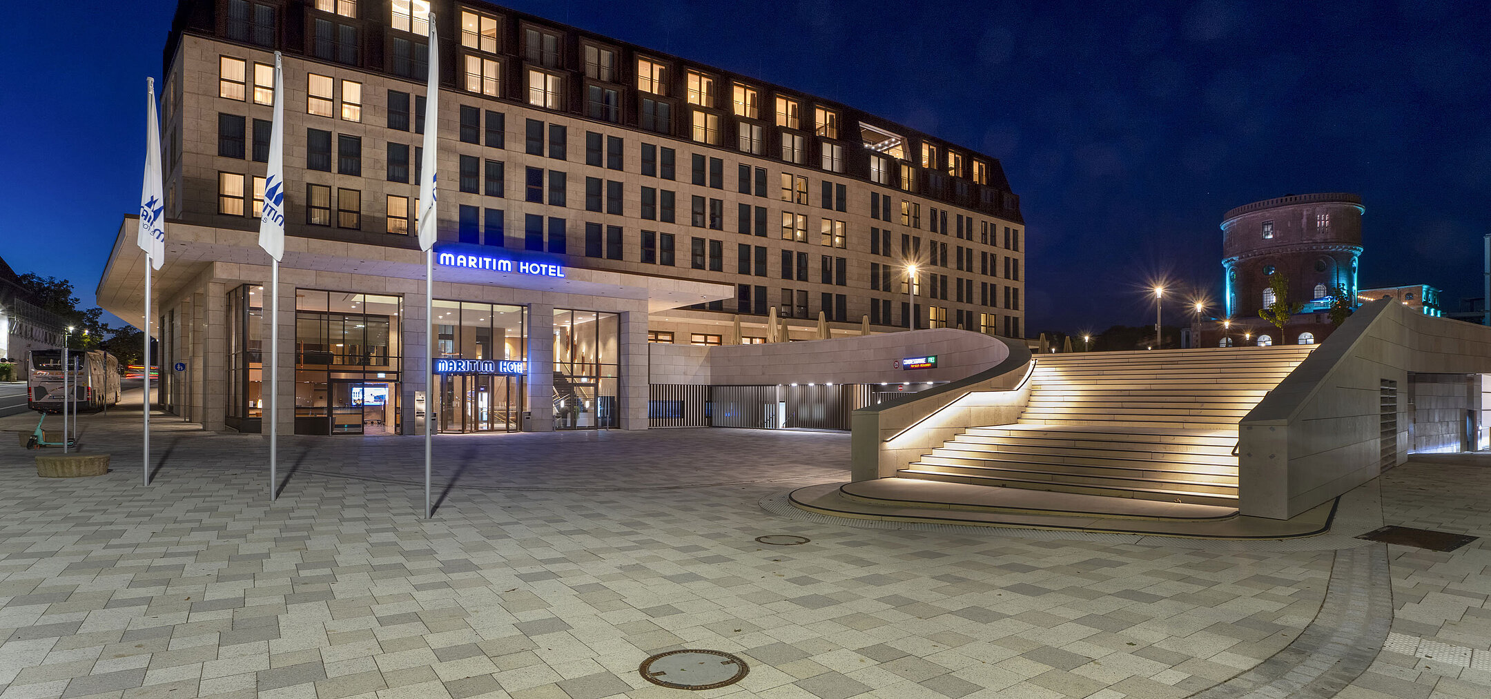 Entrée du Maritim Hotel Ingolstadt la nuit avec éclairage d’ambiance et escalier.