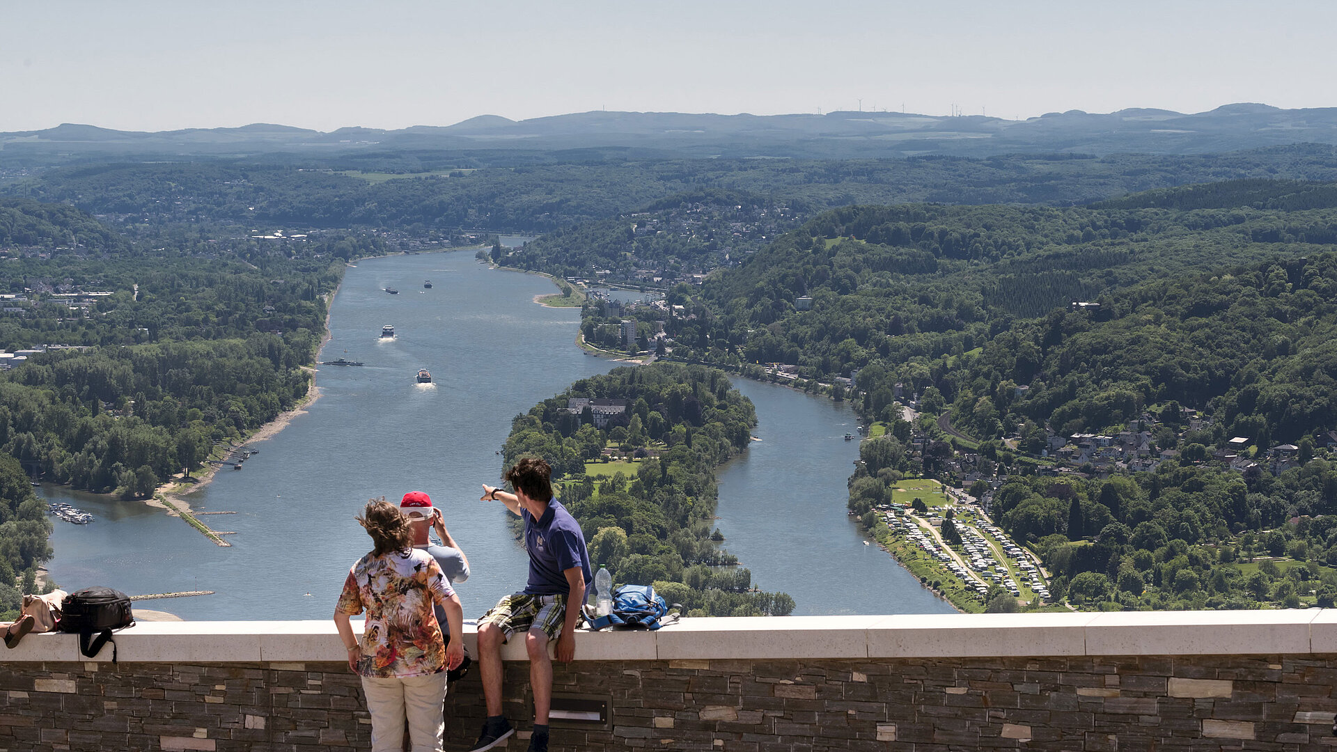 Visitors enjoy the breathtaking view from Drachenfels over the Rhine and surrounding forests.