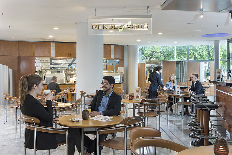  Il Café Rendezvous presso il Maritim Hotel Frankfurt con ospiti che gustano un caffè e personale cordiale.