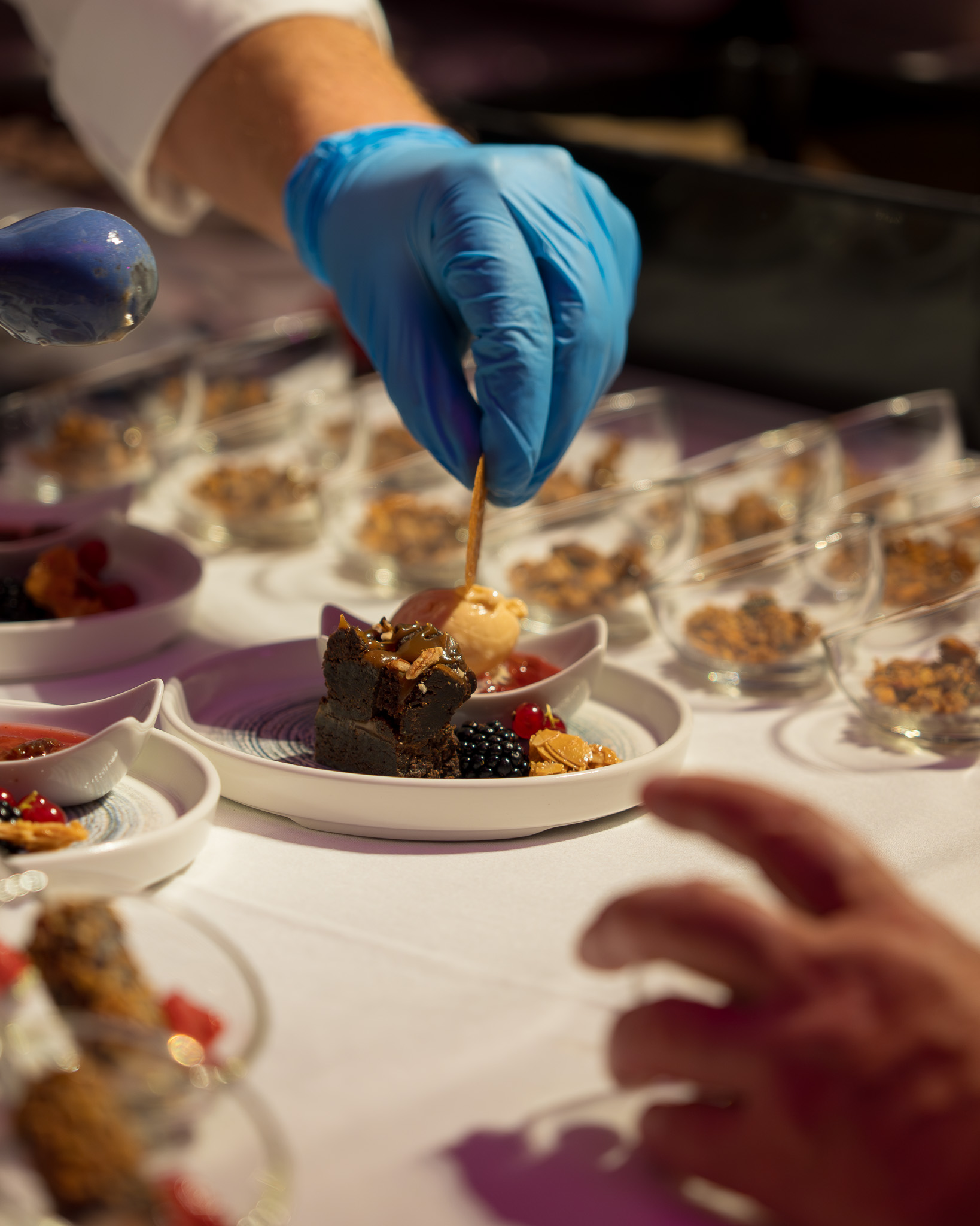 Chef plating a freshly prepared dish during a kitchen party while guests watch the preparation.