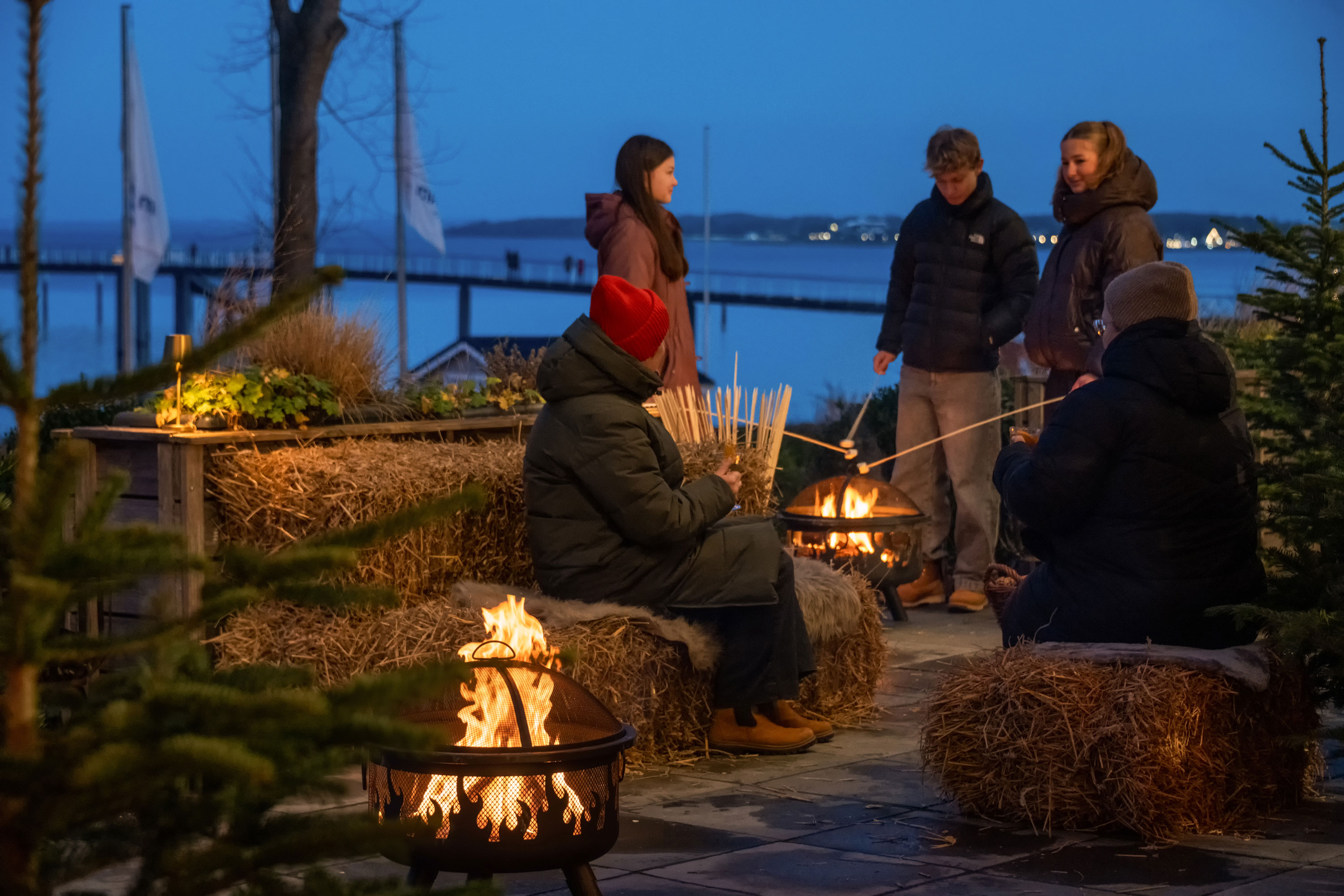 Winter magic by the Baltic Sea Guests enjoying a cosy winter atmosphere around a fire basket on a festively decorated terrace overlooking the Baltic Sea.